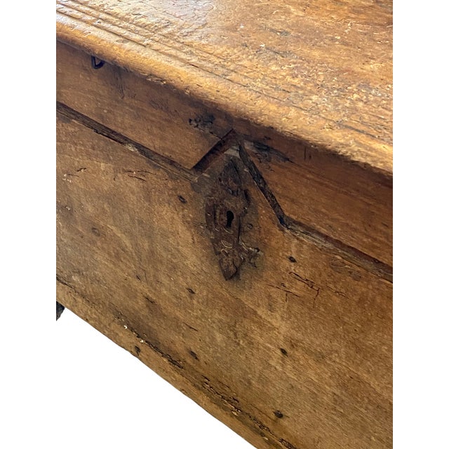 This late 1800’s antique wooden chest and storage trunk, crafted from aged pine with hand-carved details and iron...