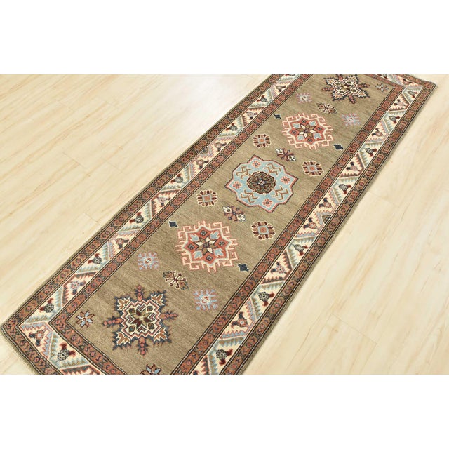 This traditional tribal geometric Caucasian Kazak runner is hand-knotted with an all-wool pile on a cotton foundation....