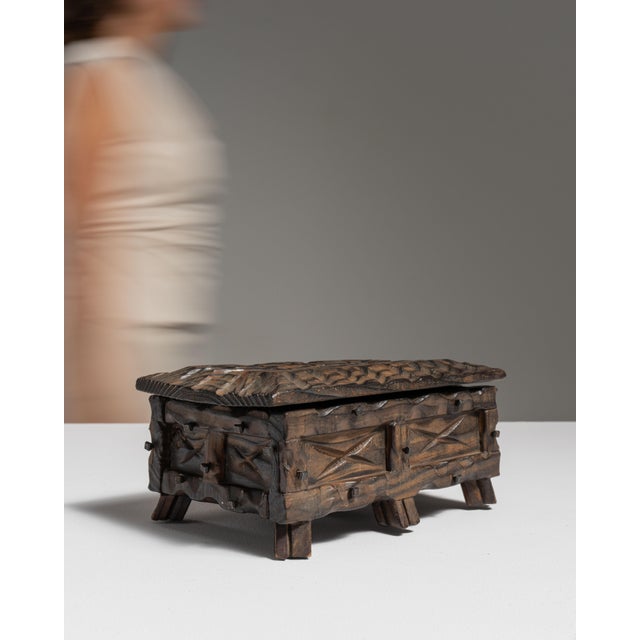 This early 20th century Spanish hand-carved wood box from France is carved in dark wood with a rustic, X-patterned front...