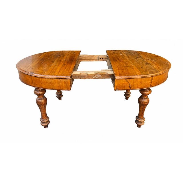 An impressive italian-made oval extendable table, crafted in the 19th century, featuring the warm tones of walnut and...