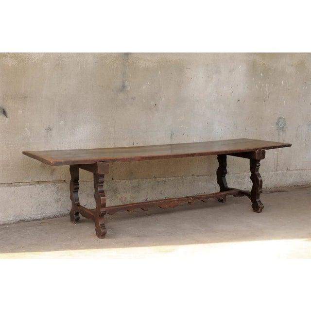 An Italian 18th century walnut dining trestle farm table with interesting cross stretcher and single board on the top.