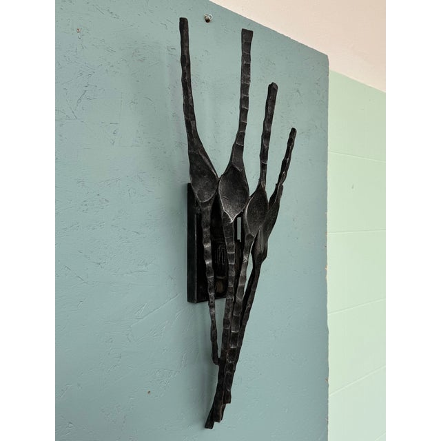 This sculpture is a Brutalist-style wall sconce, crafted from wrought iron between the 1960s and 1970s. The Brutalist...