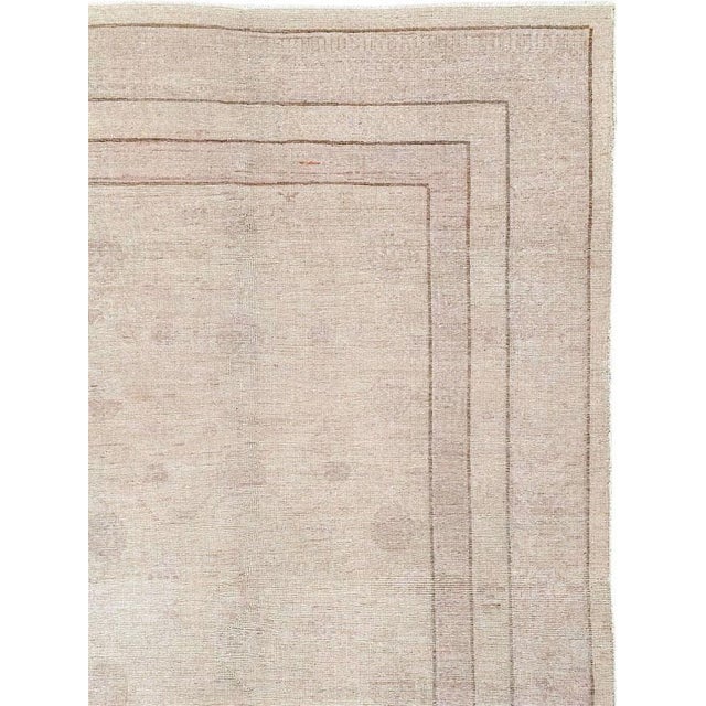 A vintage East Turkestan Khotan room size carpet handmade during the late 20th century. This Khotan is in the distressed...