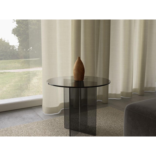 The Amami is a smoked glass side table, a study in transparency, built from Italian glass rather than stone. It trades...