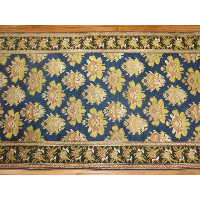 A very long early 20th century Russian Karabagh runner featuring accents in black, blue, gold and rust. The border is...