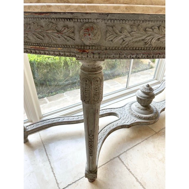 This Louis XVI Style Console Table features beautiful carvings and a painted finish with a natural limestone top. Its...