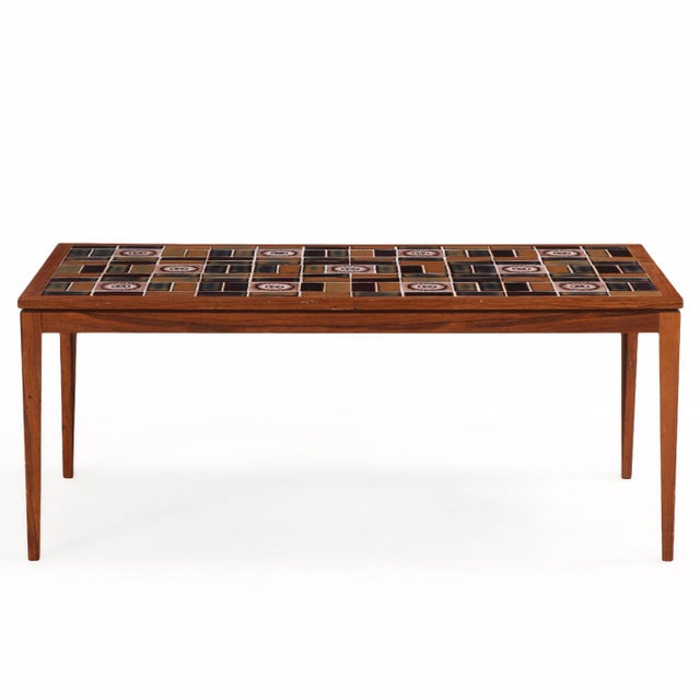 A Danish modern tile-top table executed in teak, featuring a richly toned tiled surface with a striking interplay of color...