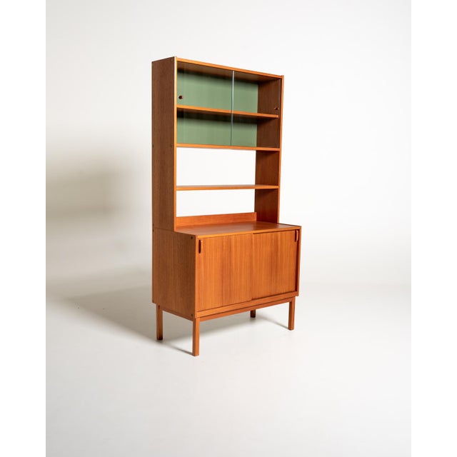 Teak bookcase with sliding doors, adjustable shelves, and an upper section with sliding glass doors. Designed by Bertil...