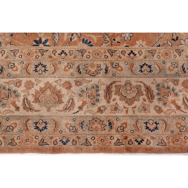 An early 20th century Persian Meshad rug, the abrashed light brown field with dramatic flowering vines, feathery leaves...