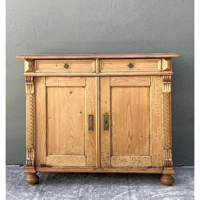 This exquisite antique European Country sideboard is a masterful display of primitive craftsmanship and Neoclassical...