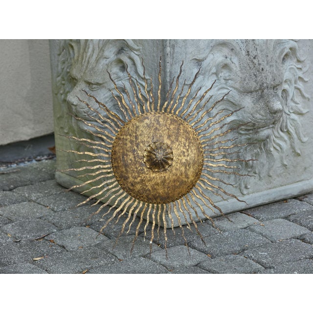 A Spanish Midcentury gilt metal sunburst chandelier with wavy rays and distressed patina. This Spanish Midcentury gilt...