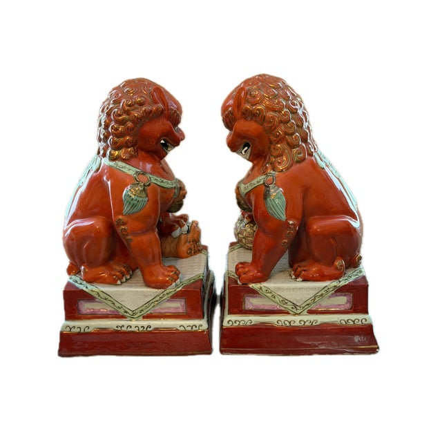 A stately pair of 20th century foo lions rendered in vibrant iron red porcelain. These guardian figures showcase...