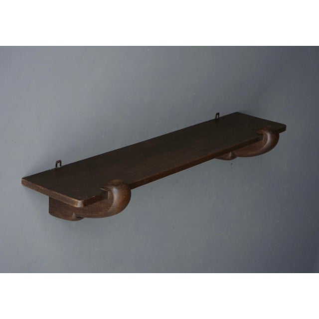 A very stylish single solid oak wall shelf in typical Amsterdam School style with chunky ornamental supports.