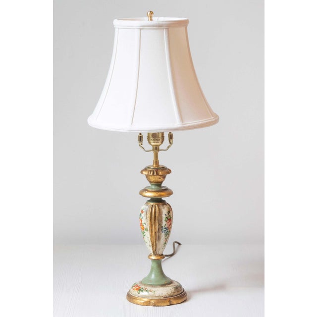 This charming mid-20th-century lamp is crafted from painted wood and adorned with polychrome floral decorations and gilded...