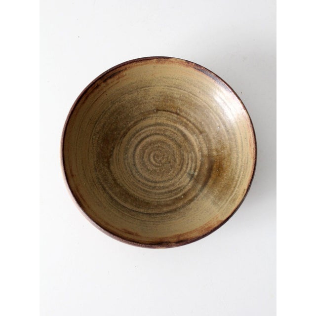 This vintage studio pottery bowl has a graceful, shallow form with a wide rim that emphasizes its sculptural simplicity....