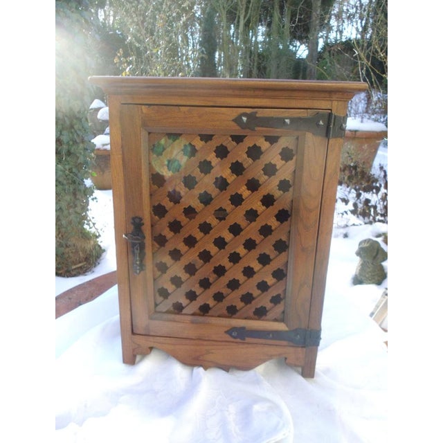 A corner wall cabinet made of walnut with a charming lattice door. It likely originates from Spain; the metal panels on...