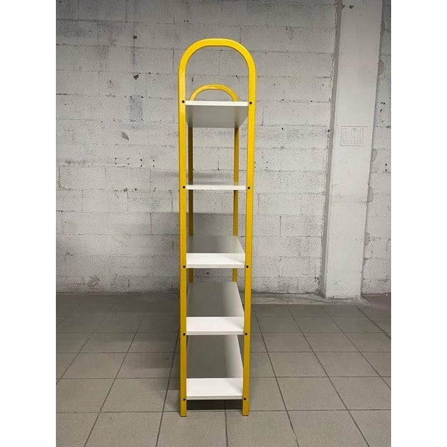 Small 80s bookcase with yellow lacquered tubular metal structure and 5 white laminate shelves. Easily placed in all rooms...