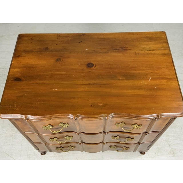 A French Provincial style fruitwood commode or chest of drawers in a rich warm brown tone with visible grain and figuring,...