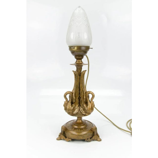 The beautifully shaped French Empire style table lamp, which is an electrified petroleum lamp, features a bronze-colored...