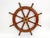 A vintage wooden ship's steering wheel in a warm reddish-brown hardwood mahogany with ten turned spokes extending past the...