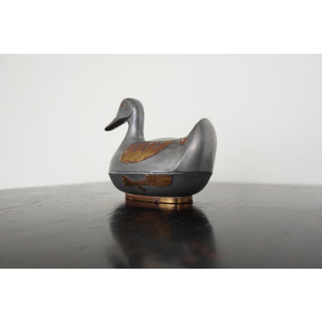 This charming vintage duck trinket box is crafted in a sleek silvery-toned metal with warm coppery and brass accents that...