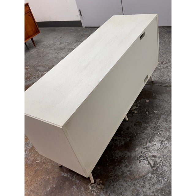 Design Plus Gallery presents a White Dang Door Console Table from Blu Dot. The media stand has a perforated steel door...