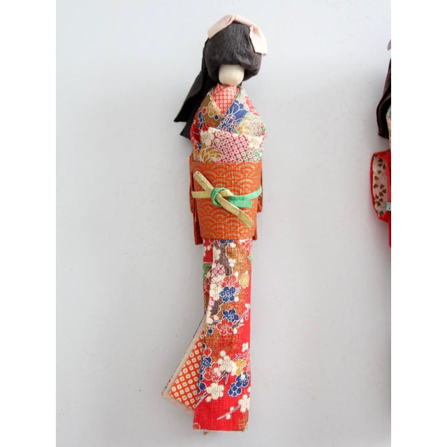 A set of three mid-century Japanese kimono dolls showcasing colorful patterned textiles, folded paper accents, and...