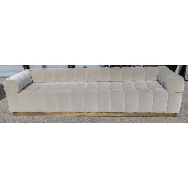 Custom “Oscar” tufted sofa with brass base, in grey velvet.