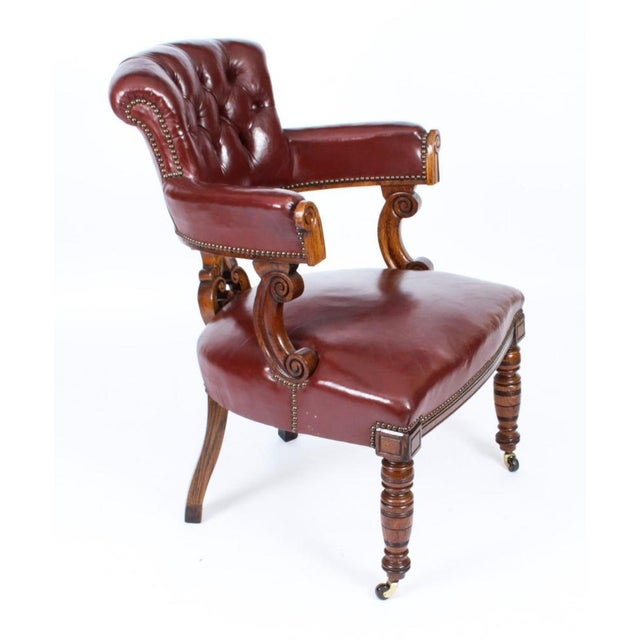 An elegant Victorian carved oak button back desk chair, upholstered in maroon leather and raised on turned legs, Circa...