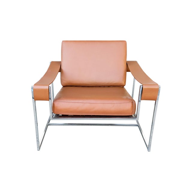 A vintage armchair in the style of Milo Baughman. This chrome-frame chair features sling arms and is upholstered in light...