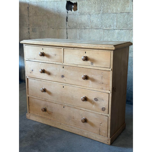 An understated scrubbed pine English chest of drawers. Late 19th Century, with two over three drawers, each with mushroom...