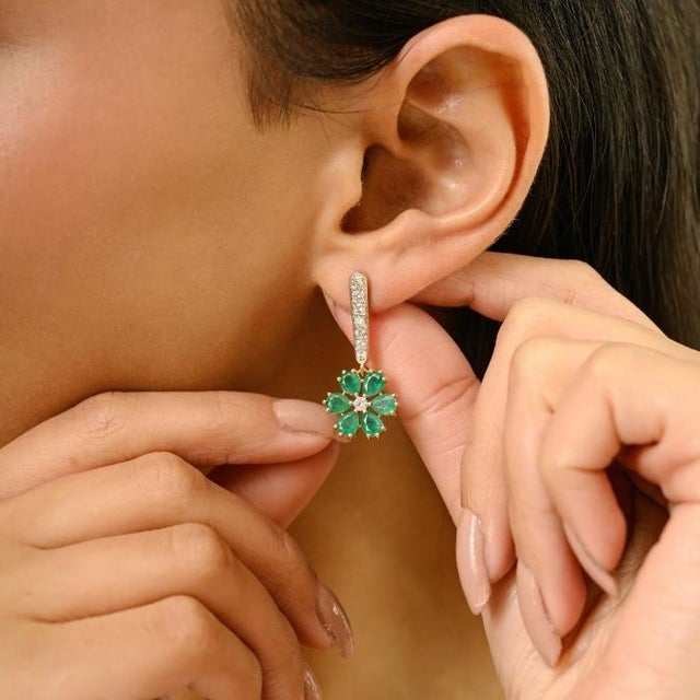 These elegant floral dangle earrings feature 12 pear cut emeralds totaling 3.02 carats, set in rich 18k yellow gold. The...