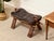 A distinctive vintage saddle stool featuring a deeply tufted black leather seat set on a substantial wood frame with...