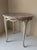 Incredibly charming cafe style side table, circa 1920s, with a carved wood braided base, white with gold leaf accents, and...
