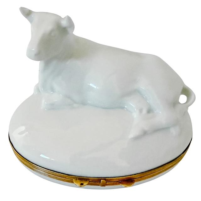 A beautiful French Limoges porcelain hinged box by Chamart, sculpted as a recumbent cow resting atop a contoured oval...