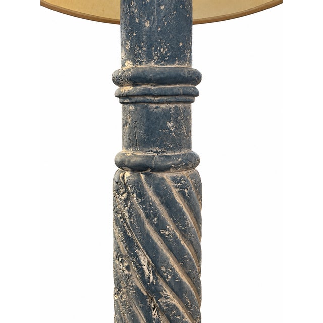 A sculptural floor lamp featuring a blue-gray spiral column, raised ring details, and a stepped circular base. Cream-toned...