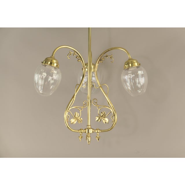 Magnificent, restored French Art Nouveau chandelier, circa 1900. This three-arm ceiling light, made of polished brass, was...