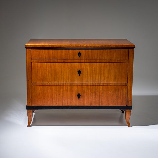 Three-drawer Biedermeier chest of drawers raised on shaped tapered square legs with ebonized moldings and escutcheons. The...