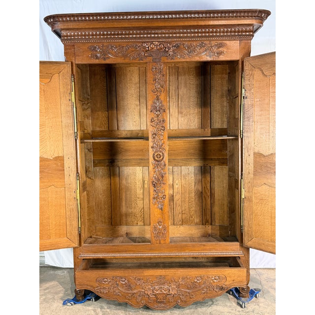 Antique oak French armoire de mariage 1840's featuring detailed floral and basket carvings throughout. The front showcases...