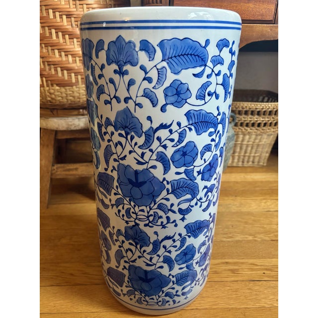 A gorgeous Chinoiserie blue and white porcelain umbrella or cane stand surrounded by florals. Made in China, Late 20th...