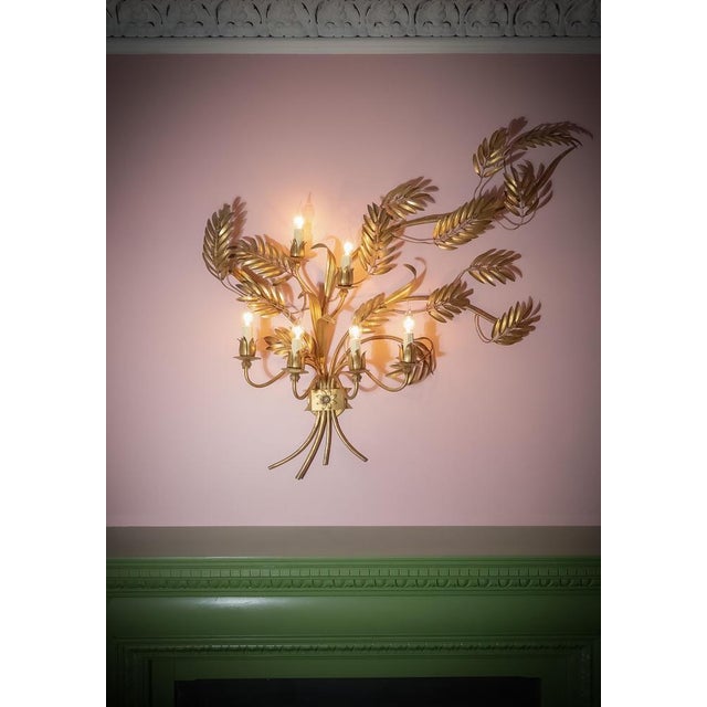 A large gilt-metal Toleware wall sconce, crafted in Italy in the 1960s, reflecting the bold glamour of Hollywood Regency...