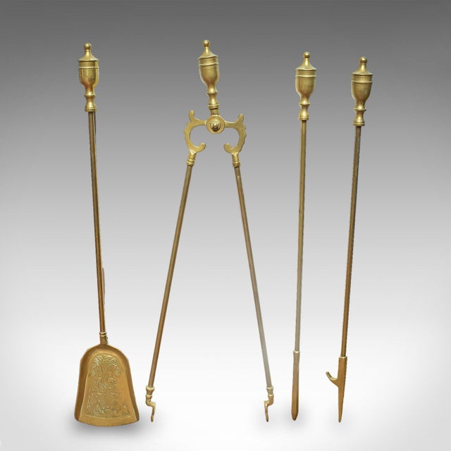 This is a set of 4 antique fireside tools. An English, brass poker duo, coal shovel and tongs with pair of tool rests,...