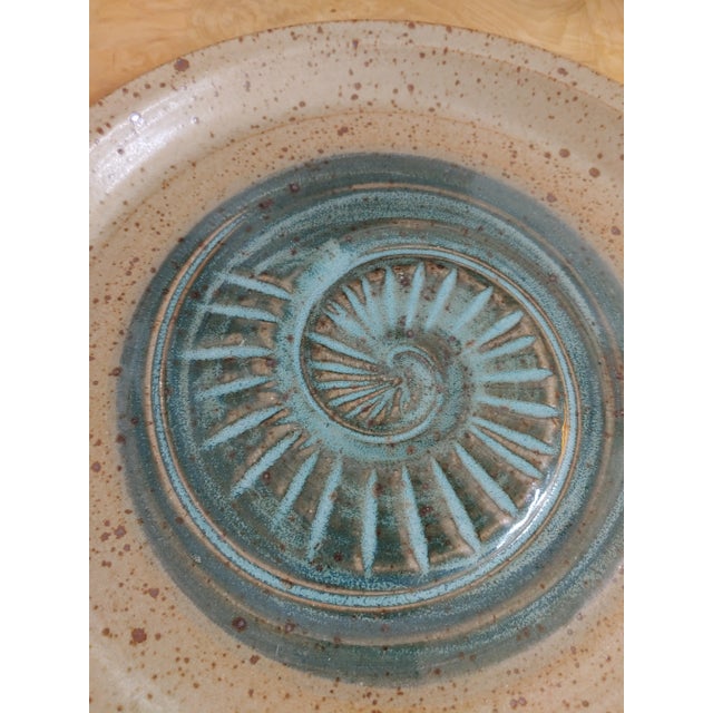 Here's a nicely executed stoneware bowl that features a seashell in the center in shades emulating the ocean. Signed on...