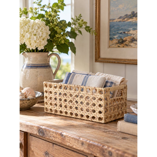 A vintage rectangular woven storage basket with an open lattice weave and natural ivory finish. Crafted from flexible...