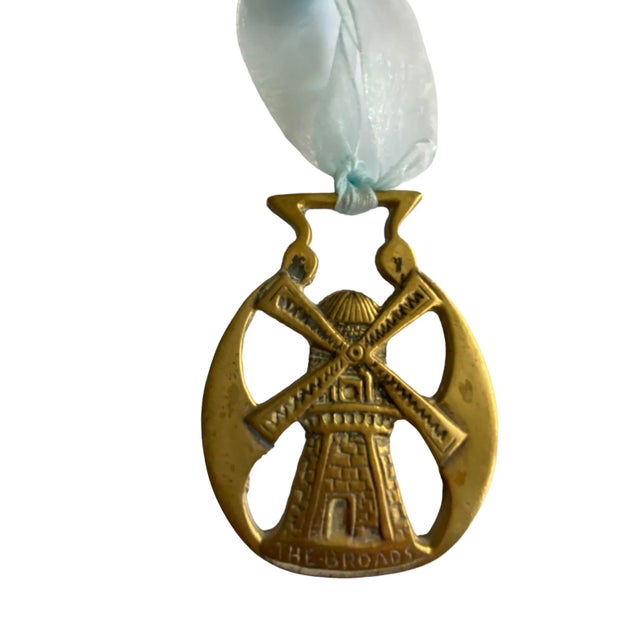 Vintage English horse brass medallion featuring a windmill. Ornament is finished with a blue raw edge silk chiffon ribbon.