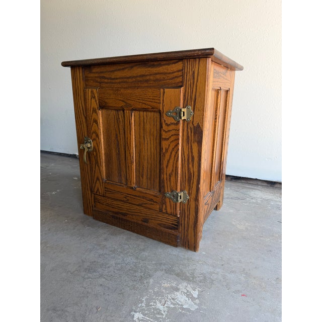 A beautifully crafted vintage Mission-style accent cabinet featuring solid oak construction, raised panel doors, and warm...