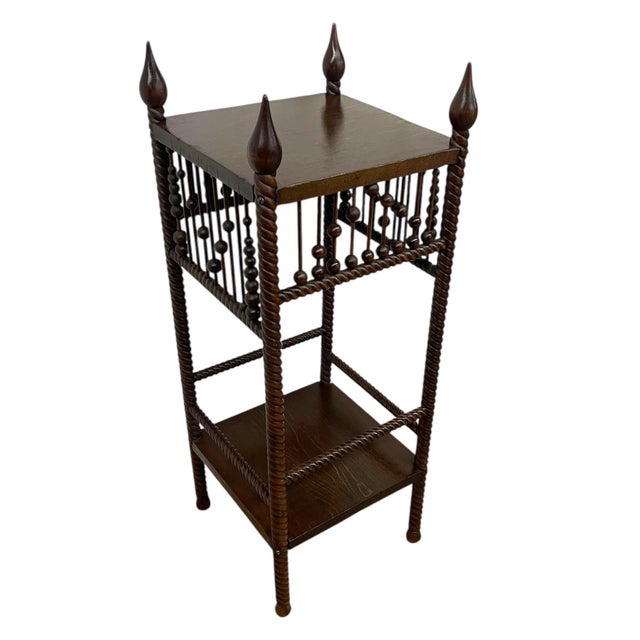 A vintage wooden plant stand or occasional table featuring classic barley twist detailing and a decorative spindle...