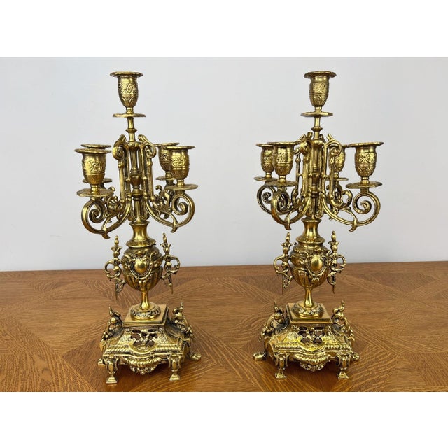 An impressive pair of Vintage brass candelabras featuring elegant five-arm candle holders with richly ornate decorative...