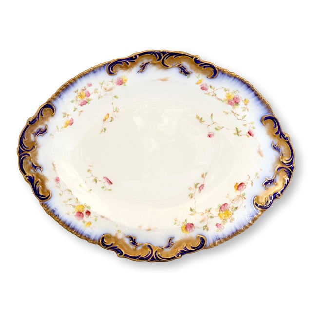 Antique English porcelain dish with a gently scalloped oval form, raised scrollwork rim, and hand-applied flow blue and...