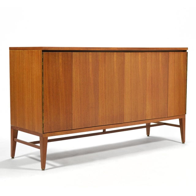 Beautiful mahogany credenza by Paul McCobb for Calvin. Two sets of tri-fold doors conceal two adjustable shelves and a...